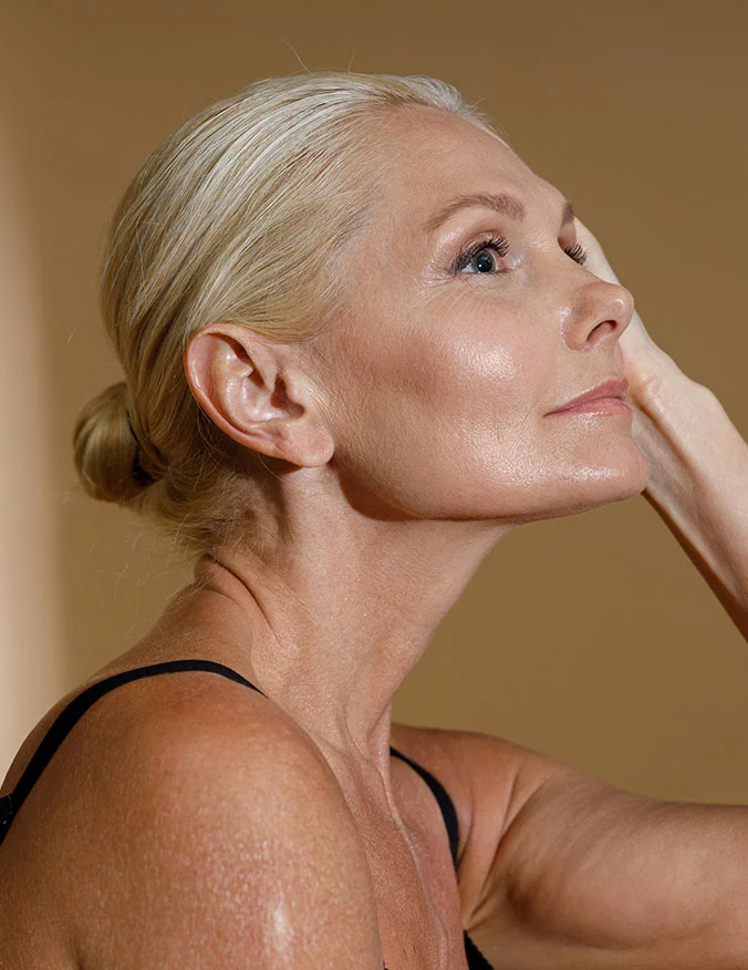 A profile shot of a blonde woman looking upward, highlighting clear skin on her neck and jawline free of visible veins or redness.