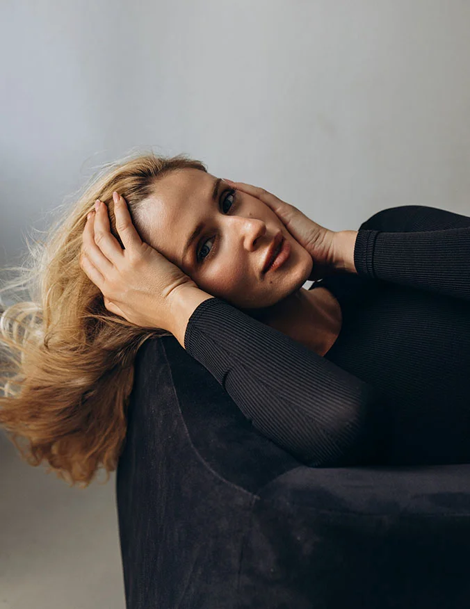 A woman lying back with her hands to her head, looking relaxed and comfortable, representing a post-treatment recovery state.